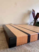 Load image into Gallery viewer, A square wooden cutting board displaying the edge view and joinery while showing the contrast between maple and wenge