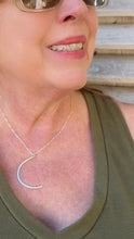 Load image into Gallery viewer, A close-up lifestyle shot of a woman wearing a delicate silver crescent moon pendant necklace, styled with an olive green tank top and sunglasses.