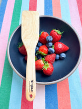 Load image into Gallery viewer, handcrafted wooden kitchen untensil in maple wood pictured with a bowl of strawberries and blue berries
